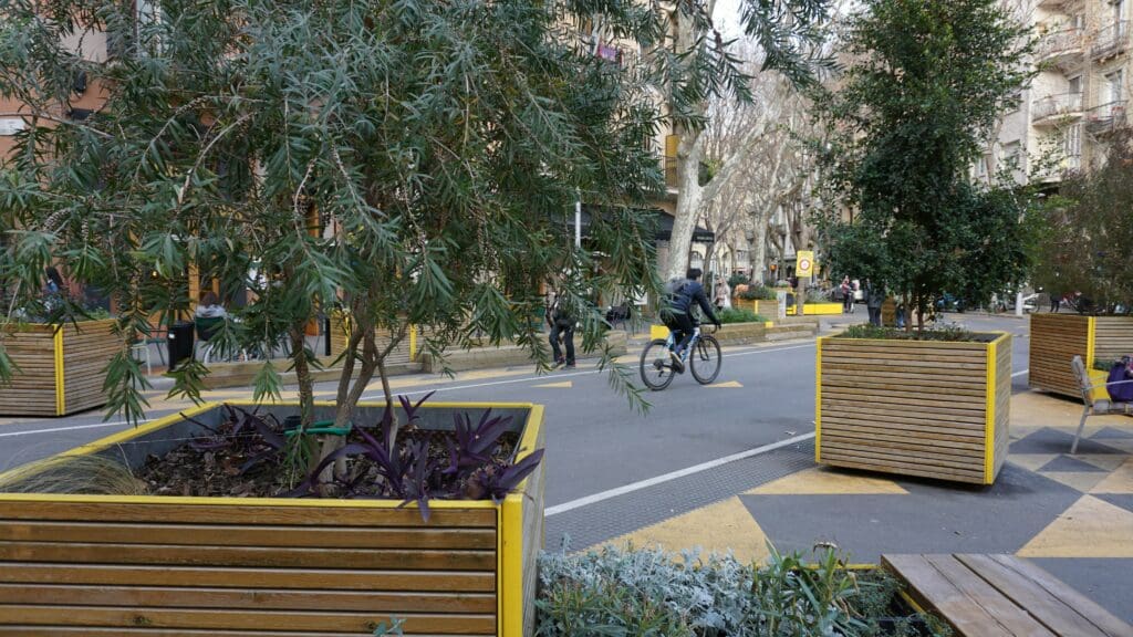 Einer der ruhigeren Plätze mit Sitzgelegenheiten zum Entspannen und geselligem Beisammensein im Grünen; Radfahrer und Fußgänger nutzen die Straße