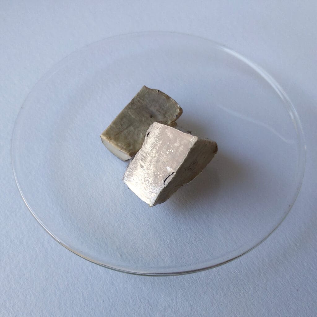 Glossy metal sodium pieces, basis for an alternative battery technology, lying on an hour glass