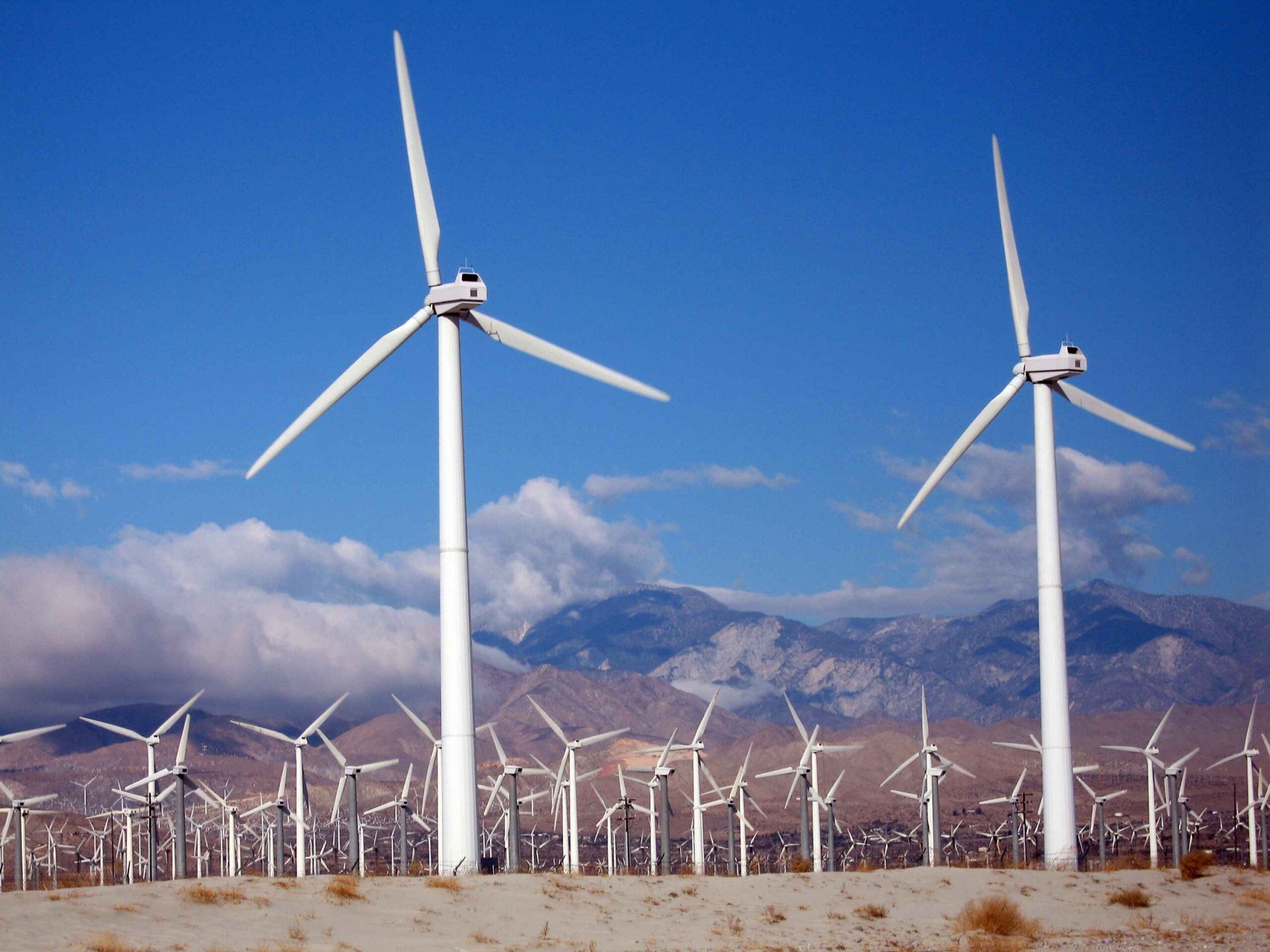 Huge conventional wind farm with white masts and three rotor blade turbines on top; airborne wind energy systems, however, are flexible, autonomous solutions