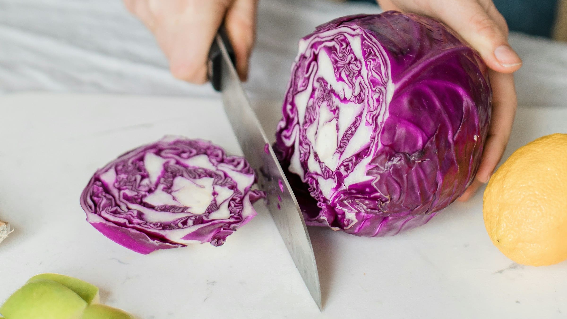 Eine Person schneidet einen Rotkohl und bereitet eine gesunde Mahlzeit zu