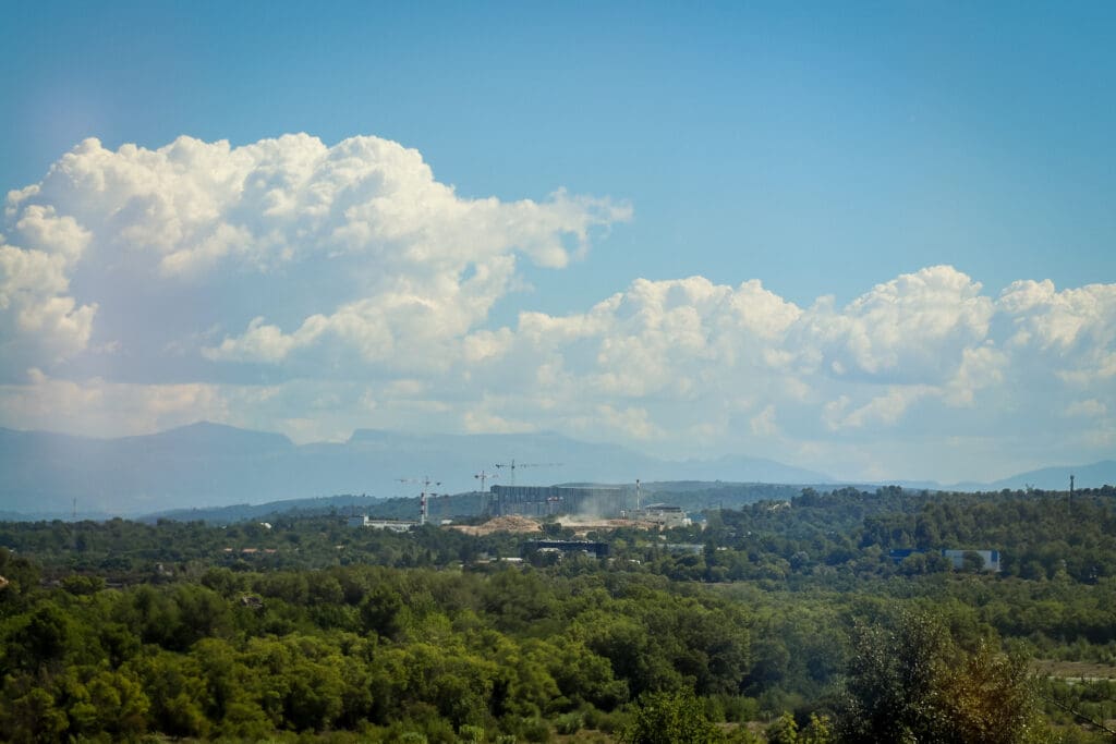 The ITER fusion plant contruction site amongst a forest, with a mountain range in the background