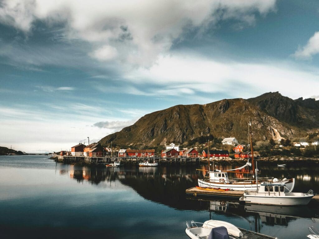 Most Norwegians are deeply connected to nature; the pictur shows a little harbor town in front of a mountain range