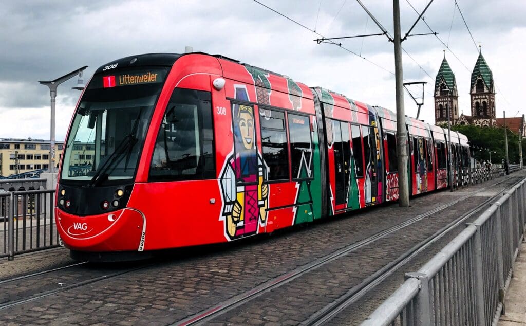 Eine rote Straßenbahn fährt in einen Vorort außerhalb der Freiburger Altstadt