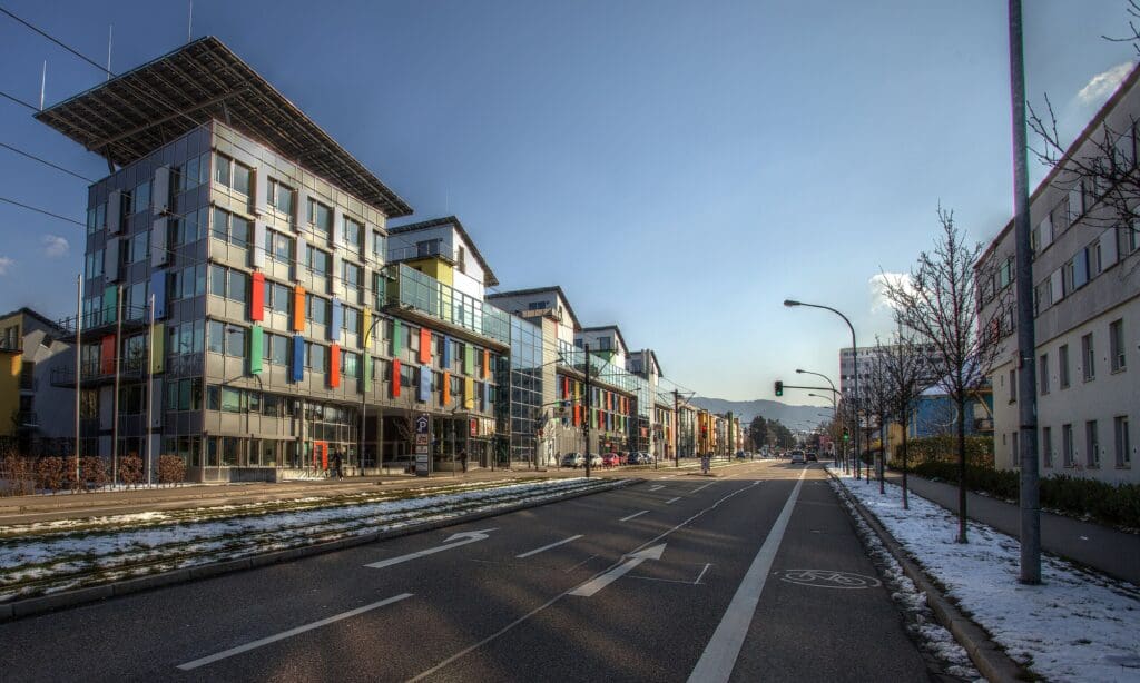 Links befindet sich das "Sonnenschiff"; vor dem bunten Komplex verläuft eine Straße mit Straßenbahnen und einem Fahrradweg