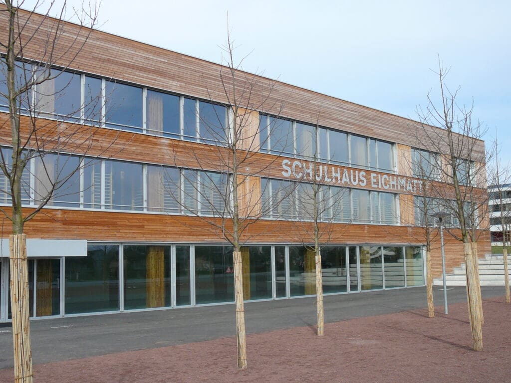Das erste Minergie-P-zertifizierte Schulgebäude der Schweiz zeichnet sich durch große, nach Süden ausgerichtete Fenster und eine Holzfassade aus