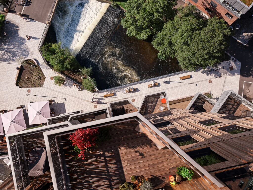 Spectacular top down view from the top of the taller tower down along the wooden facade and balconies onto a river next to the foundation