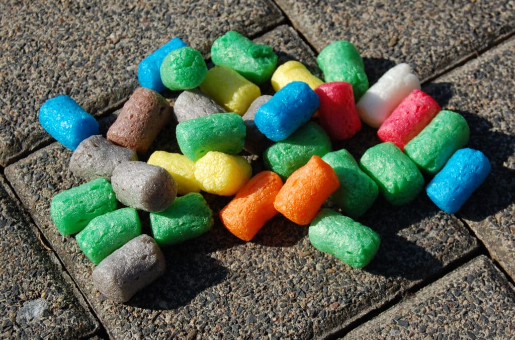 Colorful maize starch foam pieces lying on a grey pavement