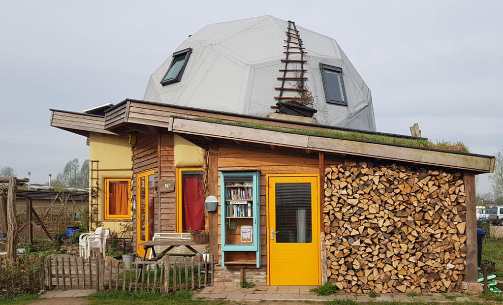 Close-up of one of the half-dome topped houses with a colorful wooden facade and a stack of firewood