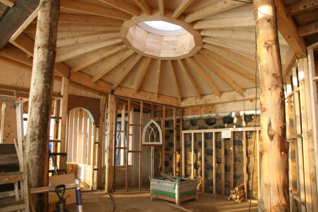 Inside view of an Aardehuizen home, the half-dome roof is a wooden structure supported by two large tree trunks. One of the walls is made of tires and clay.