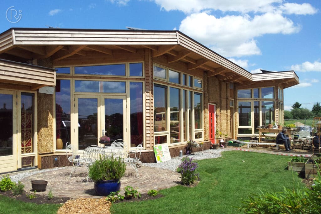 Aardehuizen building with panoramic window front and a garden; straw bales are part of the wall structure