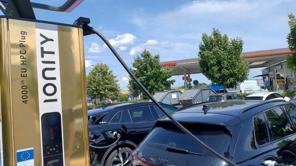 Golden 4000th Ionity fast charger at a service area, connected to a black SUV EV